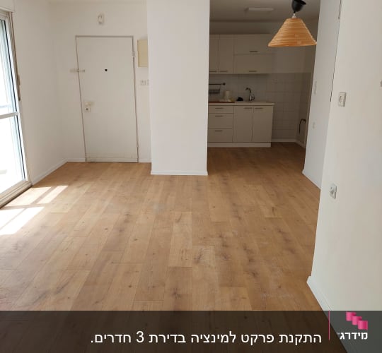 רצפת פרקט עץ בהירה בחדר ריק עם מטבח קטן